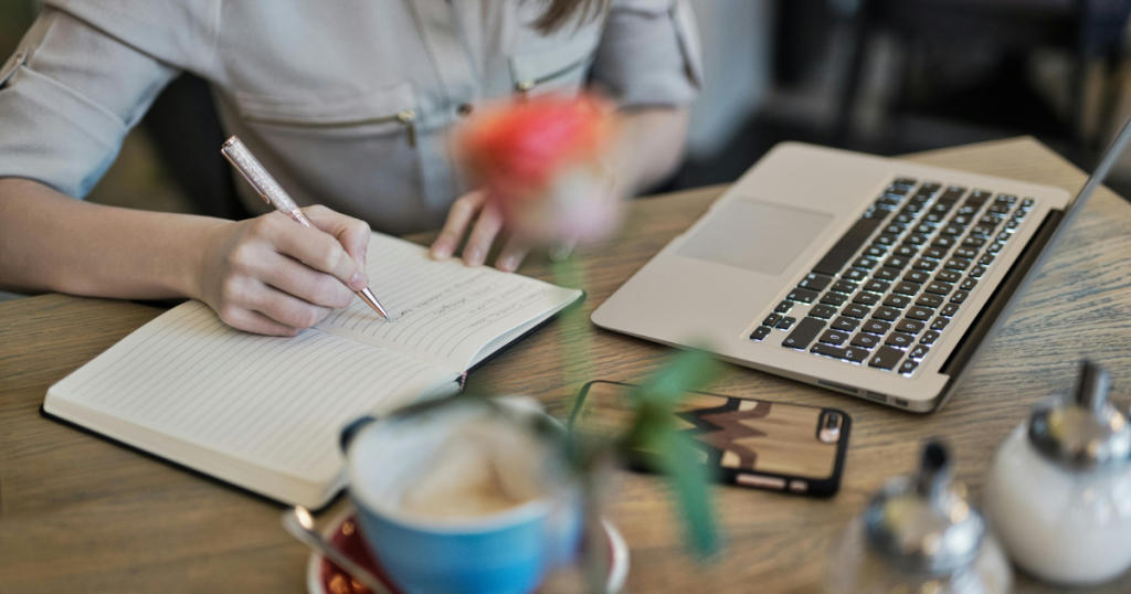 hand writing on a notebook, table with laptop